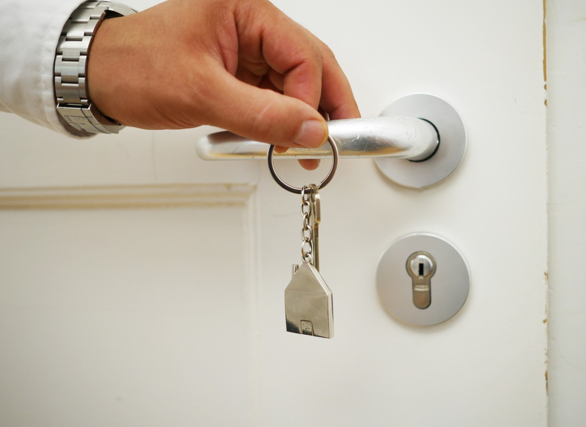 a person holding a house keychain while holding a door handle - property owners insurance