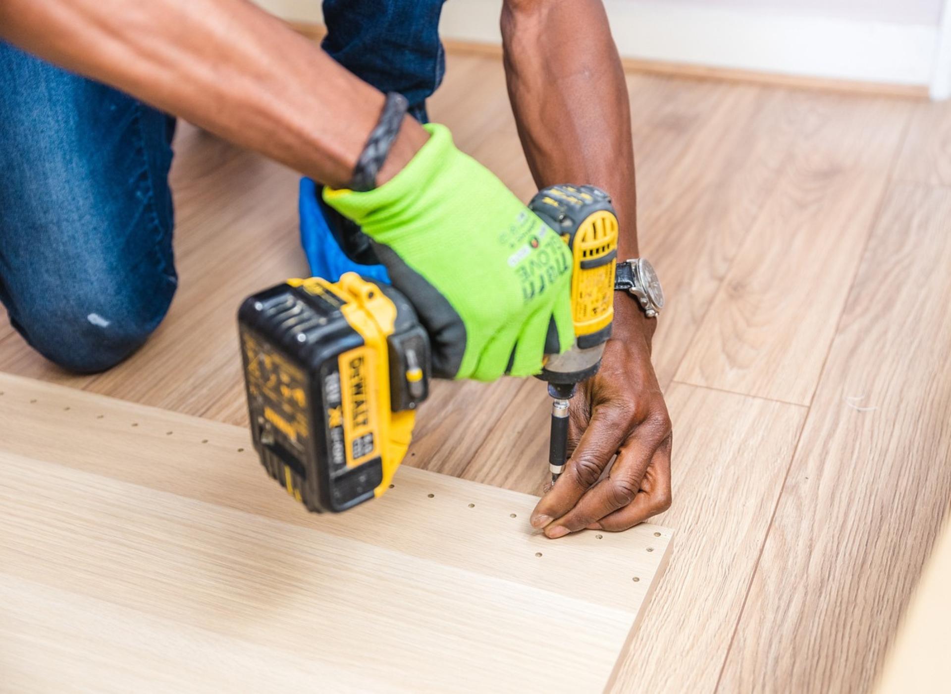 a person holding a drill and putting a screw into the floor - tradesman insurance