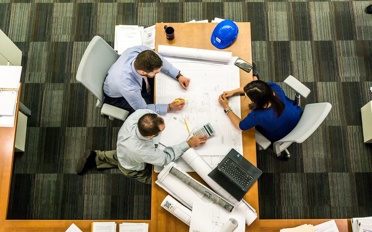 three people sat around a table looking over a shared piece of paper - liability insurance