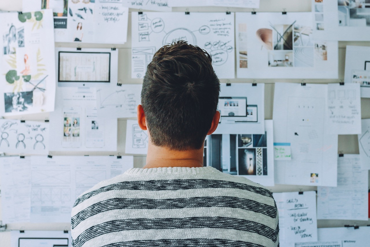 A person looking at lots of paper pinned onto the wall - commercial combined insurance